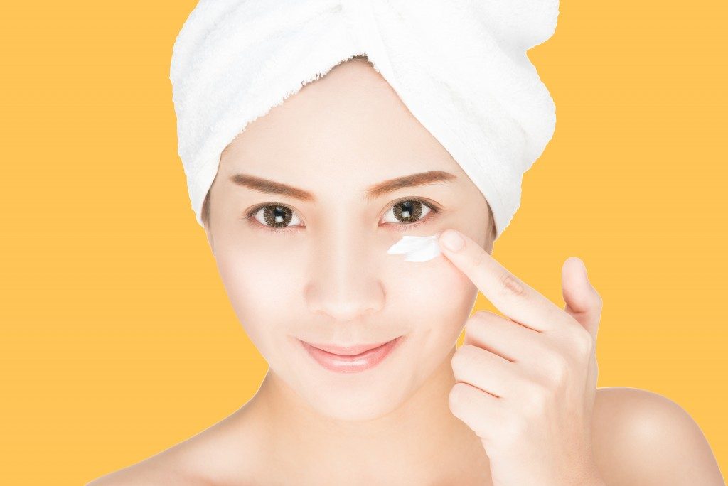 woman applying skin cream under eyes