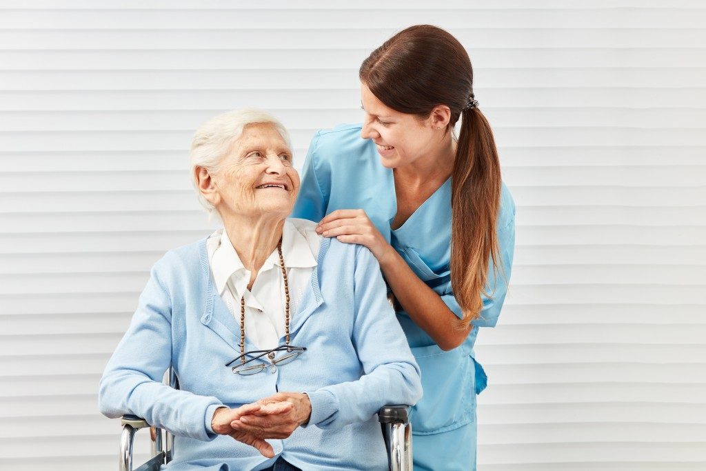 Senior woman and nurse smiling at each other