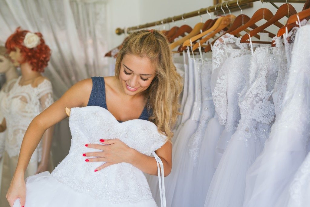 Woman choosing wedding dress in shop