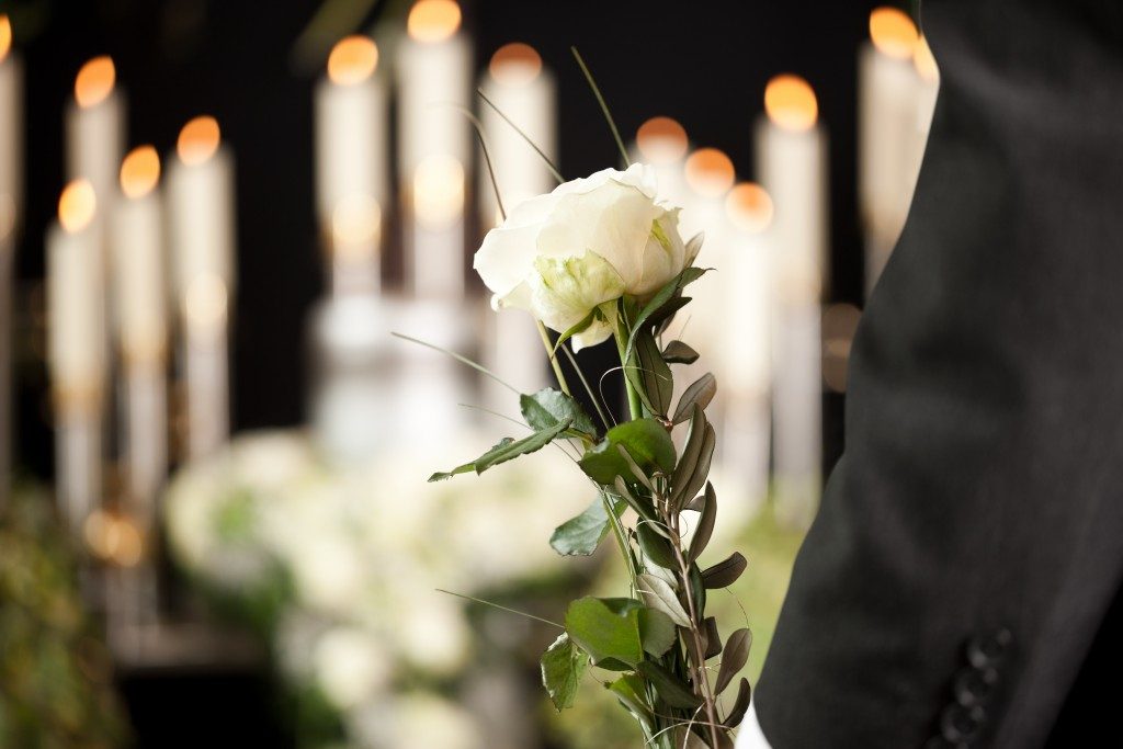 person holding a white rose in a funeral