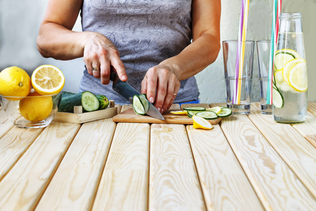 woman cutting cucumber and lemons