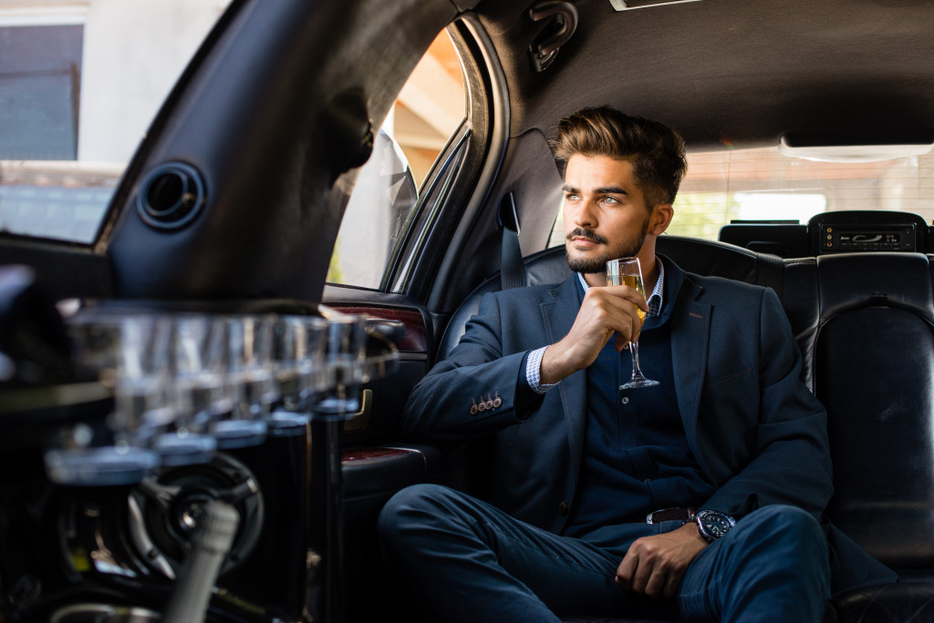 businessman in limousine drinking champagne looking out the window