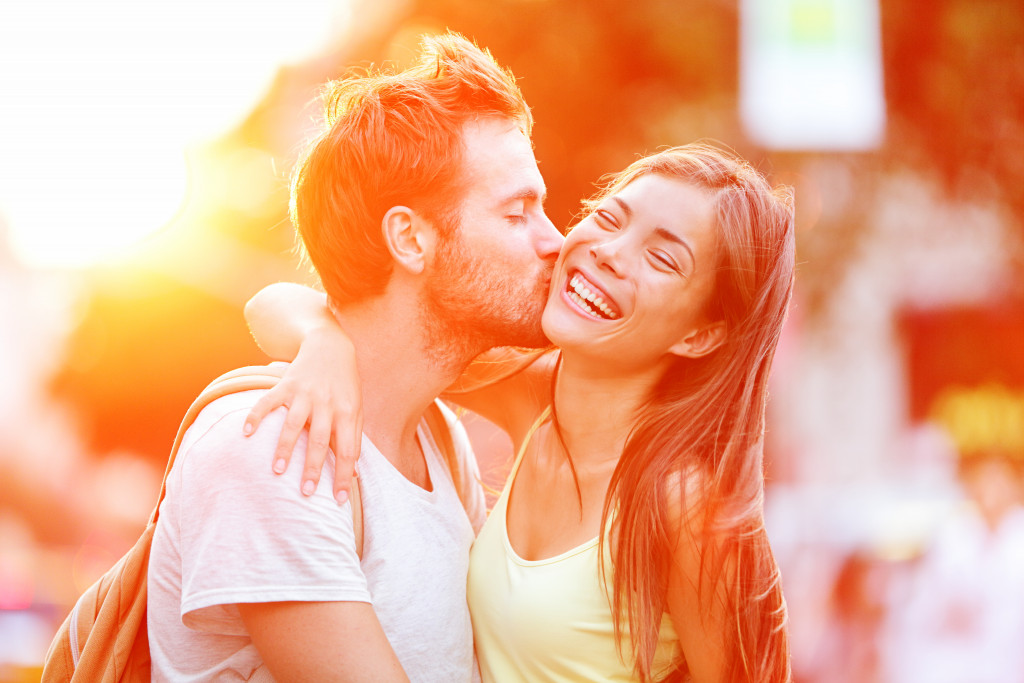 A man kissing his girlfriend on the cheek