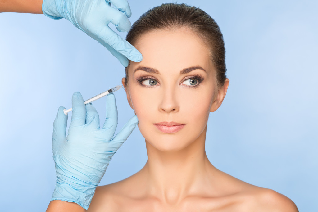 woman getting injected botox in her face by gloved hands