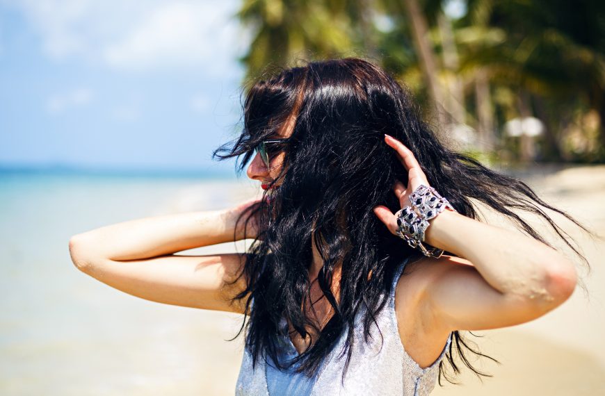 woman on the beach playfully flipping her long, black hair