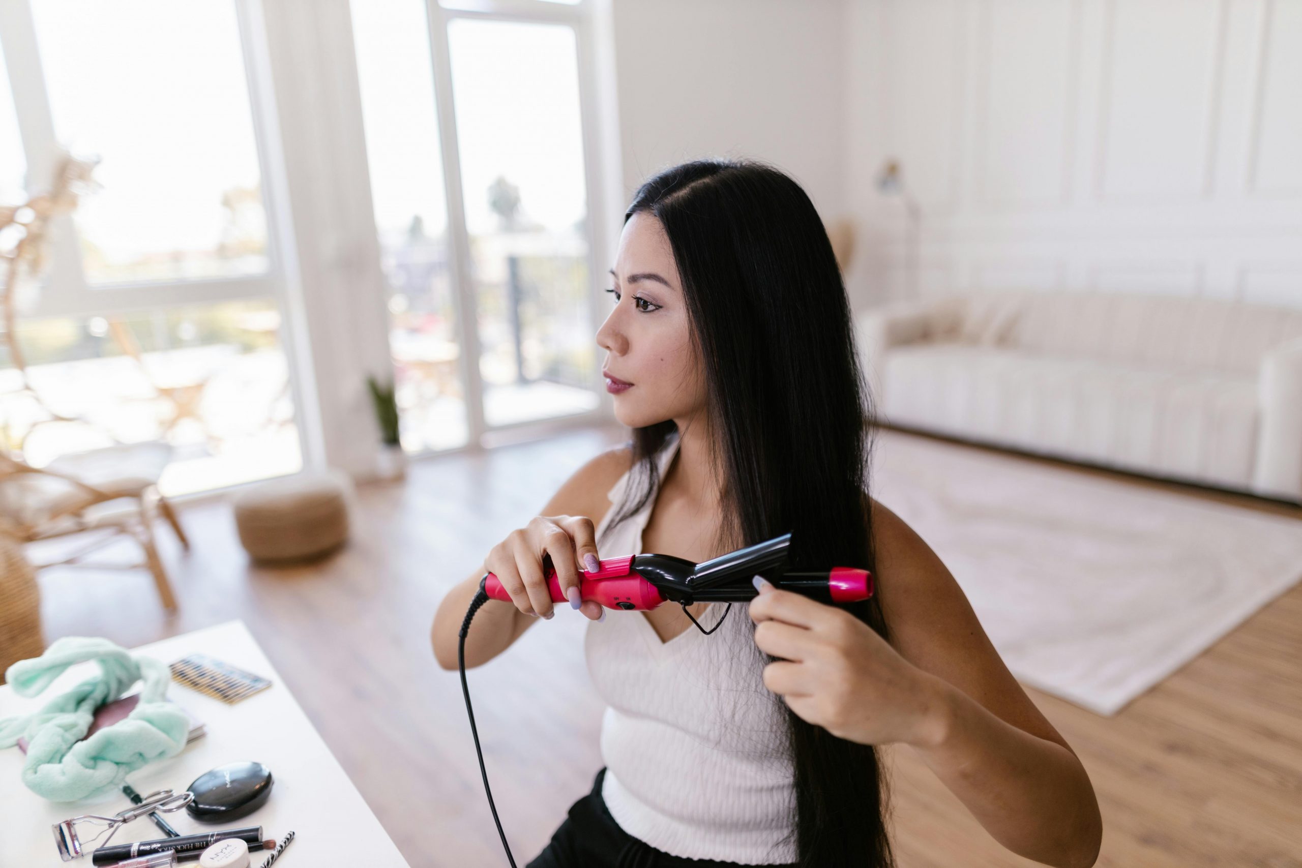 woman styling her hair with a pink hair straightener