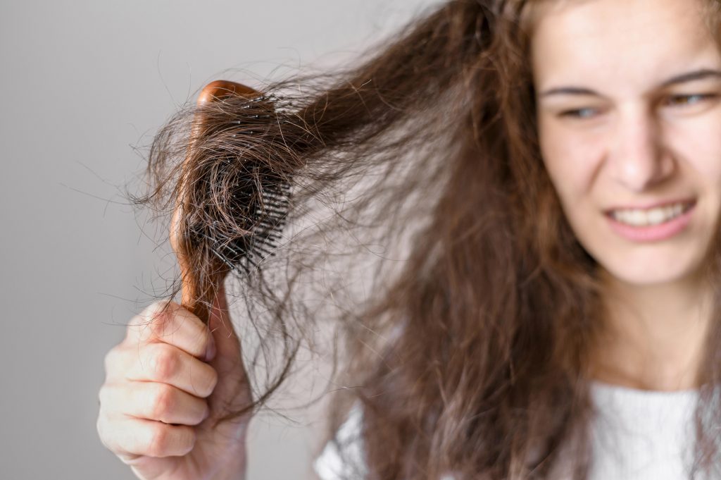 woman struggling with tangled hair caught in a brush